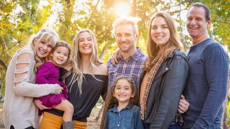 large family hugging outside | dentist near me